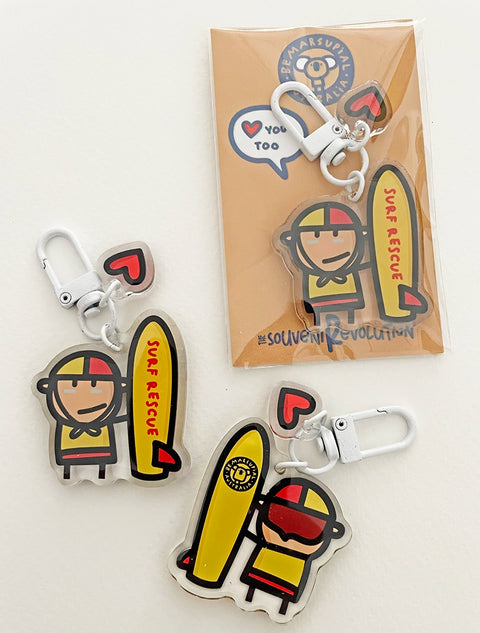 Picture of the best Australian gift for surf lovers, a tiny shiny super cute charm made of resin, illustrated with a lovely surf rescuer